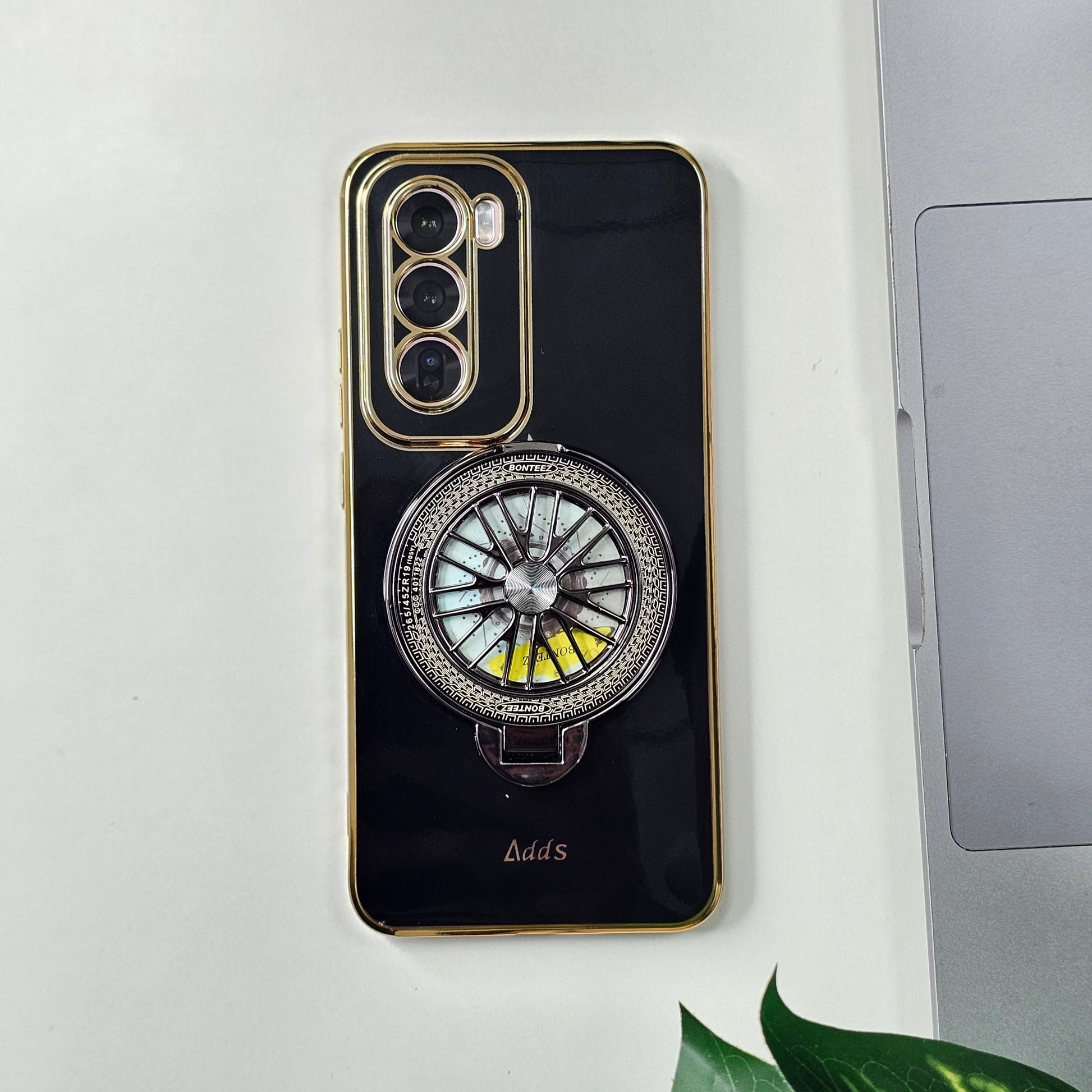 A black Oppo Reno 12 Pro 5G smartphone case with a unique design featuring a metallic circular pattern on the back.